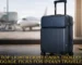 A navy blue lightweight cabin trolley luggage with a front laptop compartment standing in an airport terminal with a plane in the background.