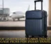 A navy blue lightweight cabin trolley luggage with a front laptop compartment standing in an airport terminal with a plane in the background.